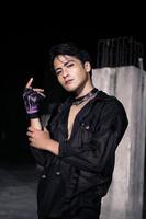 an Asian man dressed all in black and black hair posing as masculine photo