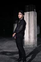 an Asian man dressed all in black and black hair posing as masculine photo