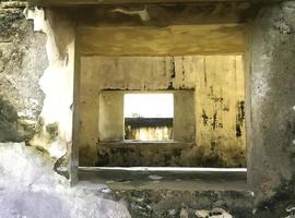 An old, abandoned building stands in silence, its history and architecture revealed through a single window on a sunny day photo