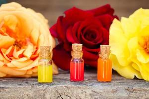 Bottles of essential oil and roses on old wooden background. photo