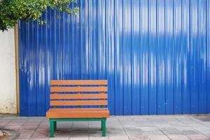 Bench in front of a blue metal wall with space for text. photo