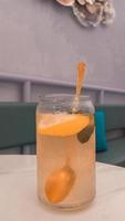 A glass of lemonade with a spoon in it and a glass with a blue pillow on the table photo