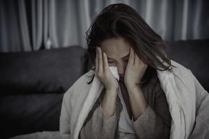 Asian sick woman sit on the sofa stay at home,The woman felt bad, wanted to lie down and rest,high fever photo