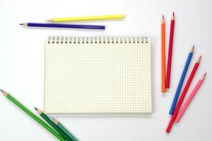 Graph book with colored pencils or pastel lined up on white background. Learning, study and presentation concept. photo