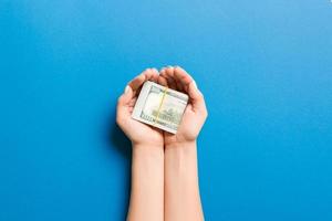 Top view of dollars in female palms on colorful background. Small pension concept photo