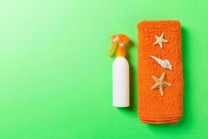 Summer beach flat lay accessories. Sunscreen bottle cream, towel and seashells on colored Background. Travel holiday concept with copy space photo