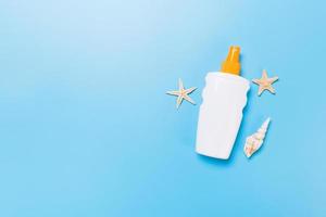 sunscreen cream with starfish and seashells in bottles on blue background, top view photo