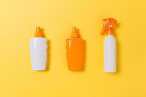 flat lay concept of summer travel vacation. Sunscreen bottle mock up on yellow background top view with copy space photo