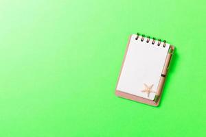 notebook with sseashells on pink background top view flat lay. Planning summer holidays, tourism and vacation concept photo