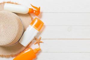 botellas de protección solar con estrellas de mar y sombrero para el sol sobre una mesa de madera blanca con espacio para copiar. vista superior de accesorios de salud de viaje foto