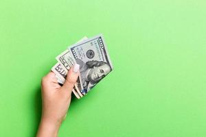 Top view of female hand holding a pack of money on colorful background. Different dollars. Business concept with empty space for your design. Charity and tips concept photo