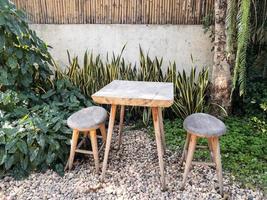 el de madera silla y mesa conjunto para café hora en el tropical jardín, foto