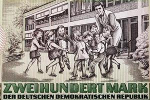 Schoolyard with eight children and a teacher from East German money photo
