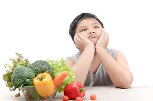 boy with expression of disgust against vegetables photo