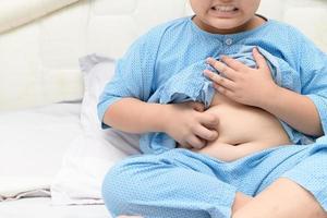 Scratching his belly in obese boy on bed photo