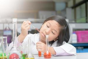 student in lab coat making experiment with test tube photo