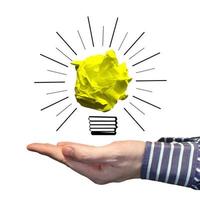 Light Bulb Icon Made with Crumpled Paper and Human Hand - Idea, Creativity Concept photo