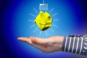 Light Bulb Icon Made with Crumpled Paper and Human Hand - Idea, Creativity Concept photo