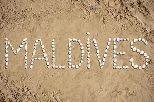 Maldivas - palabra hecho con piedras en arena foto