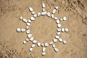 Sun Shape Made with Stones on Sand photo