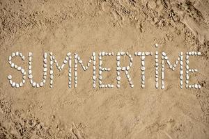 Hora de verano - palabra hecho con piedras en arena foto