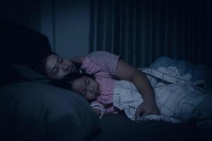 Dad and daughter sleep on the bed in bedroom,Watch cartoon with phone,Father day concept,Single dad,listen tale before sleep photo