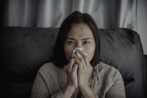 Asian sick woman sit on the sofa stay at home,The woman felt bad, wanted to lie down and rest,high fever photo