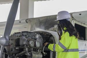 técnico arreglando el motor del avión, ingeniería aeroespacial femenina revisando los motores de los aviones, el mantenimiento mecánico asiático inspecciona el motor del avión foto