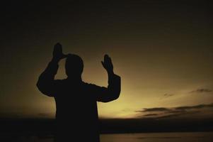 Silhouette Young asian muslim man praying on sunset,Ramadan festival concept photo