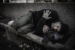 un hombre asiático no tiene hogar en la calle lateral, un extraño tiene que vivir solo en la calle porque no tiene familia. foto