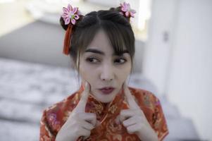 retrato hermosa mujer asiática en vestido cheongsam, gente de tailandia, concepto de feliz año nuevo chino, dama asiática feliz en vestido tradicional chino foto