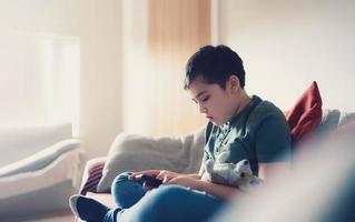 Education concept,School kid using mobile phone readying story from internet,Boy studying online learning at home,Child using cell phone playing game or chatting with friends, Homeschooling photo