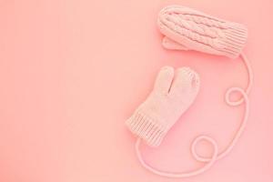 Close-up pink mittens and shaped of string on pink background. Lifestyle and warm feelings concept. Valentine day. Monocolor romantic pattern. Winter theme. Flat lay composition. Top view. Copy space photo