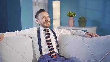 elegante e bello uomo seduta su divano solo a casa e sognare di contento giorni. video