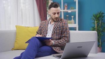 stanco uomo d'affari Lavorando a casa utilizzando il computer portatile e ottenere sopraffatto. uomo Lavorando con il computer portatile a casa ottenere annoiato e depresso a partire dal opera. video