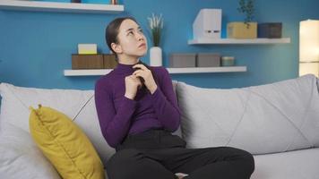 An Asian schizophrenic woman is afraid of her hallucinations. Mental illnesses. The Asian schizophrenic woman sitting alone in the living room begins to fear the hallucinations. video