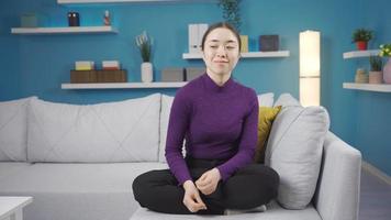 Asian woman sitting on sofa dancing calmly and happy. Vibrant Asian woman dancing by herself on the sofa at home. video