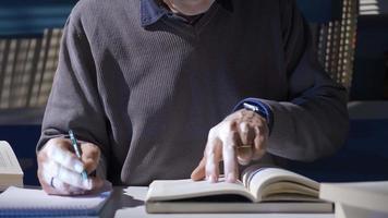 de oud Mens is lezing een historisch en wetenschappelijk boek Aan zijn Onderzoek in zijn studie. een volwassen mannetje onderzoeker lezing een boek verzamelt informatie Aan een onderwerp van interesse. video