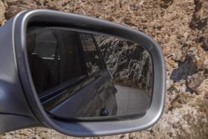 view on road and rocks in wind mirror of car photo