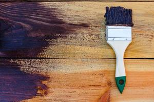 Brush on wooden background. Board half painted. photo