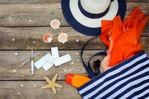 Summer women's beach accessories for your sea holiday and pill on old wooden background. Concept of medication required in journey photo