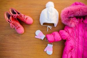 Children's winter clothes warm pink jacket, hat, mittens, boots. Top view. photo