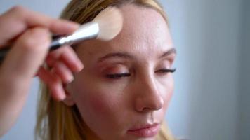 trucco artista si applica polvere e fa il correzione di il viso forma per il ragazza video