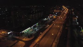 View from the height to the illuminated busy road and night city, multi-storey houses. Ukraine video