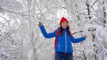 Lonely tourist girl walking on a winter snow-covered coniferous forest in the mountains. Frosty weather. Slow motion video