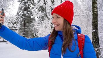 Lonely tourist girl walking on a winter snow-covered coniferous forest in the mountains. Frosty weather. Slow motion video