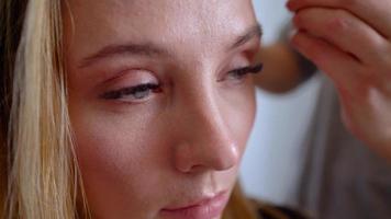 trucco artista si applica polvere e fa il correzione di il viso forma per il ragazza video