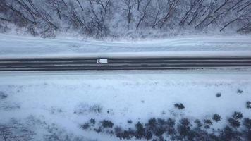 Aerial view on car driving through winter forest road. Scenic winter landscape video