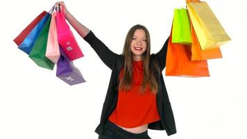 fêmea comprador segurando multicolorido compras bolsas em branco fundo dentro estúdio. vamos ir compras conceito video