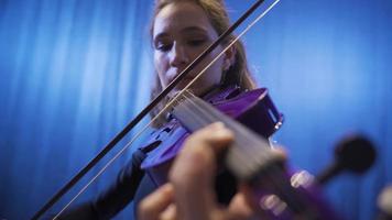 Nahansicht von Musiker Frau spielen Violine auf Bühne. komponieren, Herstellung Musik. Frau spielen Violine im Oper oder dunkel Musik- Halle. klassisch Musik. Musik- Performance beim das Oper. video